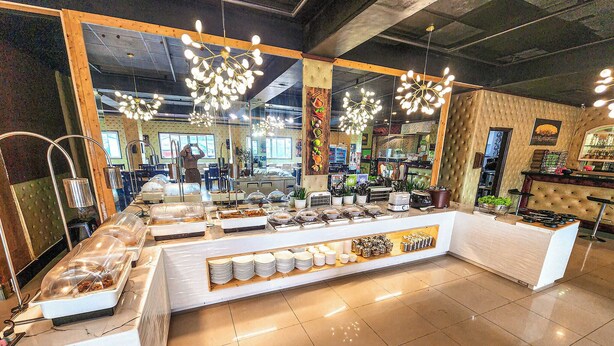 A buffet area with a variety of food items, a mirror, and a seating area with a cushioned bench. - Hotel Urban-Khotel Kurban Hotel (Baguio)