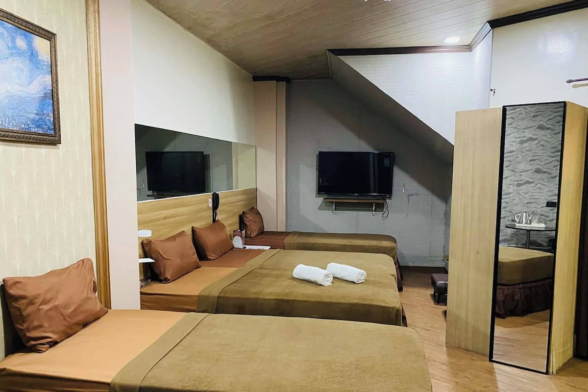 Une chambre d’hôtel avec deux lits, un téléviseur à écran plat, un miroir et une petite table avec une bouilloire.