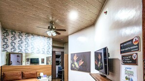 A hotel room with a wooden floor, a bed, a ceiling fan, and artwork on the walls. - Hotel Urban-Khotel Kurban Hotel (Baguio)