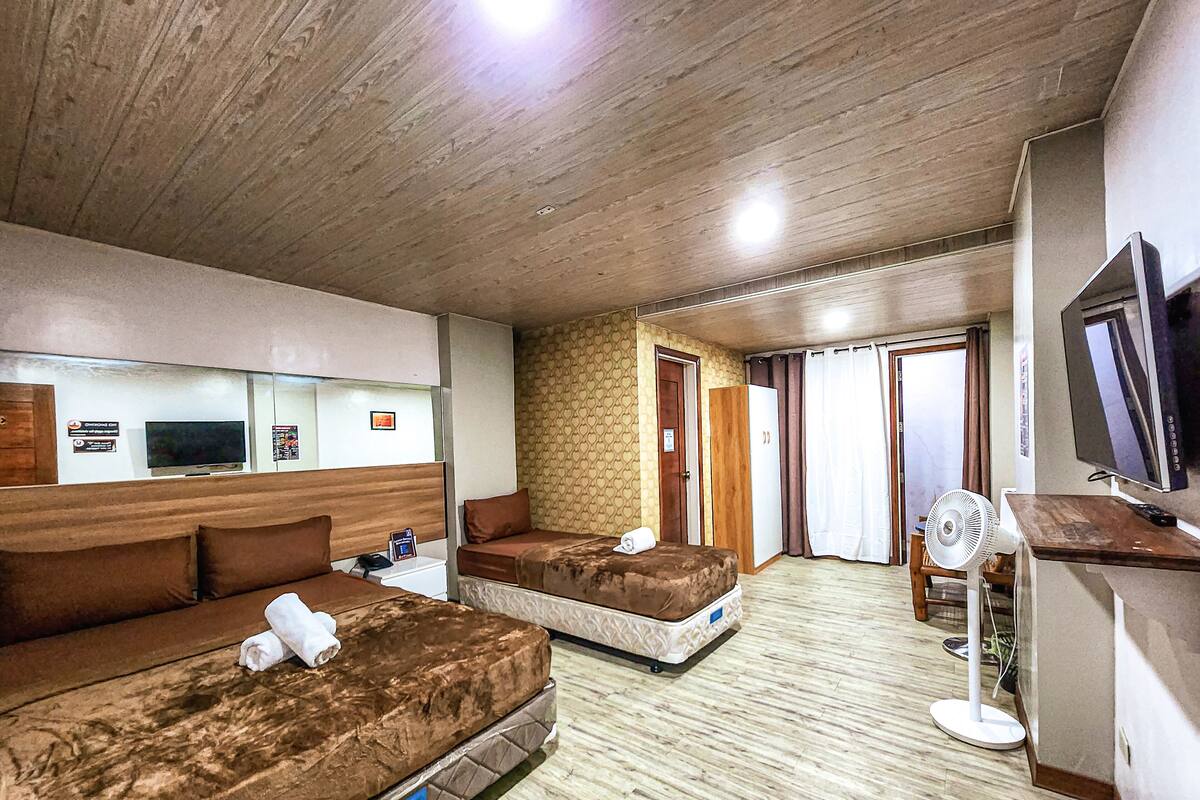 Une chambre d’hôtel avec deux lits, une télévision, un bureau et un ventilateur.