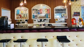 A bar area with stools, a counter with various bottles, and hanging lights. - Hotel Urban-Khotel Kurban Hotel (Baguio)