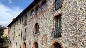 A stone building with arched windows and balconies, a paved walkway, and a clear sky. - Vacation house with pool and garden (Campiglia Marittima)
