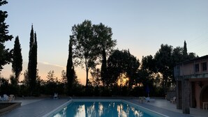 A rectangular swimming pool with a tiled deck, surrounded by trees and a stone building. - Vacation house with pool and garden (Campiglia Marittima)