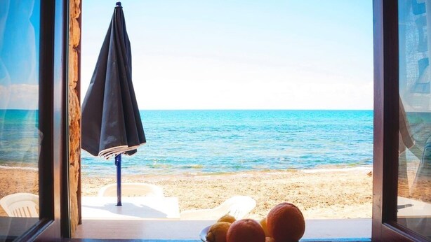 A window view of a beach with a bowl of fruit on a table. - Apollo's Terraces Beach apartments less than 20 m from the sea!Sirocco (Marinella di Selinunte)