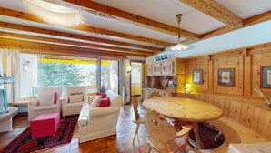 Een gezellige kamer met een houten plafond, een ronde houten tafel en een bank met kussens.