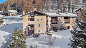Een hotel met meerdere verdiepingen en balkons, gelegen in een besneewd bergachtig gebied.
