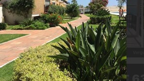 Un edificio residencial con varios balcones, un camino pavimentado y abundante vegetación.