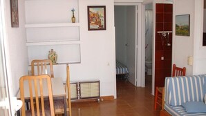 A living room with a sofa, chairs, a radiator, and a door leading to another room.