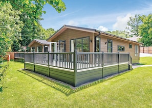 Ein eingeschossiges Haus mit Terrasse, großen Fenstern und einem umzäunten Garten.