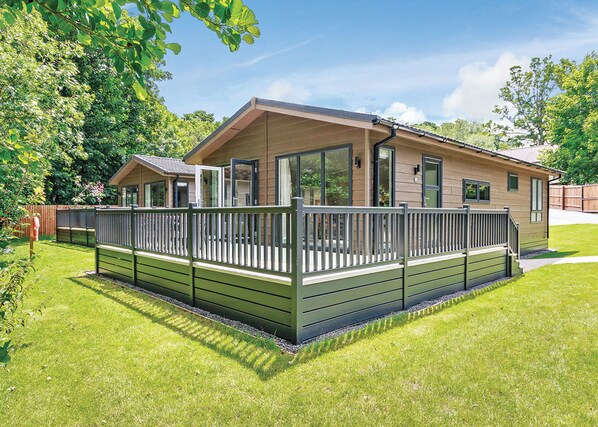 Ein eingeschossiges Haus mit Terrasse, großen Fenstern und einem umzäunten Garten.