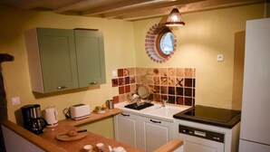 A compact kitchen with a wooden countertop, a sink, a stove, and a green cabinet.