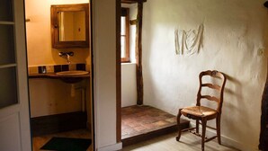 A rustic bathroom with a wooden door, a sink, and a chair.