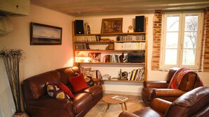 A living room with a brown leather sofa, a wooden coffee table, and a bookshelf filled with books and decorative items.