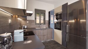 Eine moderne Küche mit einem Edelstahl-Kühlschrank, einem eingebauten Backofen und einem Fenster über der Spüle.