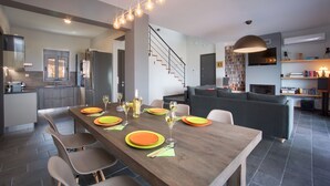 Eine moderne Küche mit Essbereich, einer Treppe und einem Wohnzimmer mit Sofa und Unterhaltungssystem.