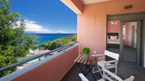 Ein Balkon mit Meerblick, einem Tisch mit Stühlen und einem Blumentopf.