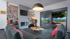 Ein modernes Wohnzimmer mit einem grauen Sofa, einem Couchtisch und einer Bücherwand voller Bücher.