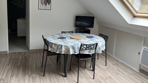 A dining area with a round table, chairs, a TV, and a ceiling skylight. - T2bis Apartment - Near center - 4/6 people - Mountain view (Cauterets)