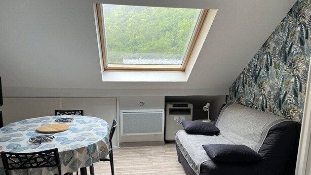 A small, cozy room with a skylight, a round table with chairs, a sofa, and a radiator. - T2bis Apartment - Near center - 4/6 people - Mountain view (Cauterets)