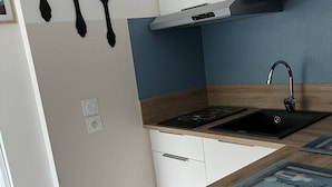 A modern kitchen with a black sink, wooden countertop, and white cabinets. - T2bis Apartment - Near center - 4/6 people - Mountain view (Cauterets)
