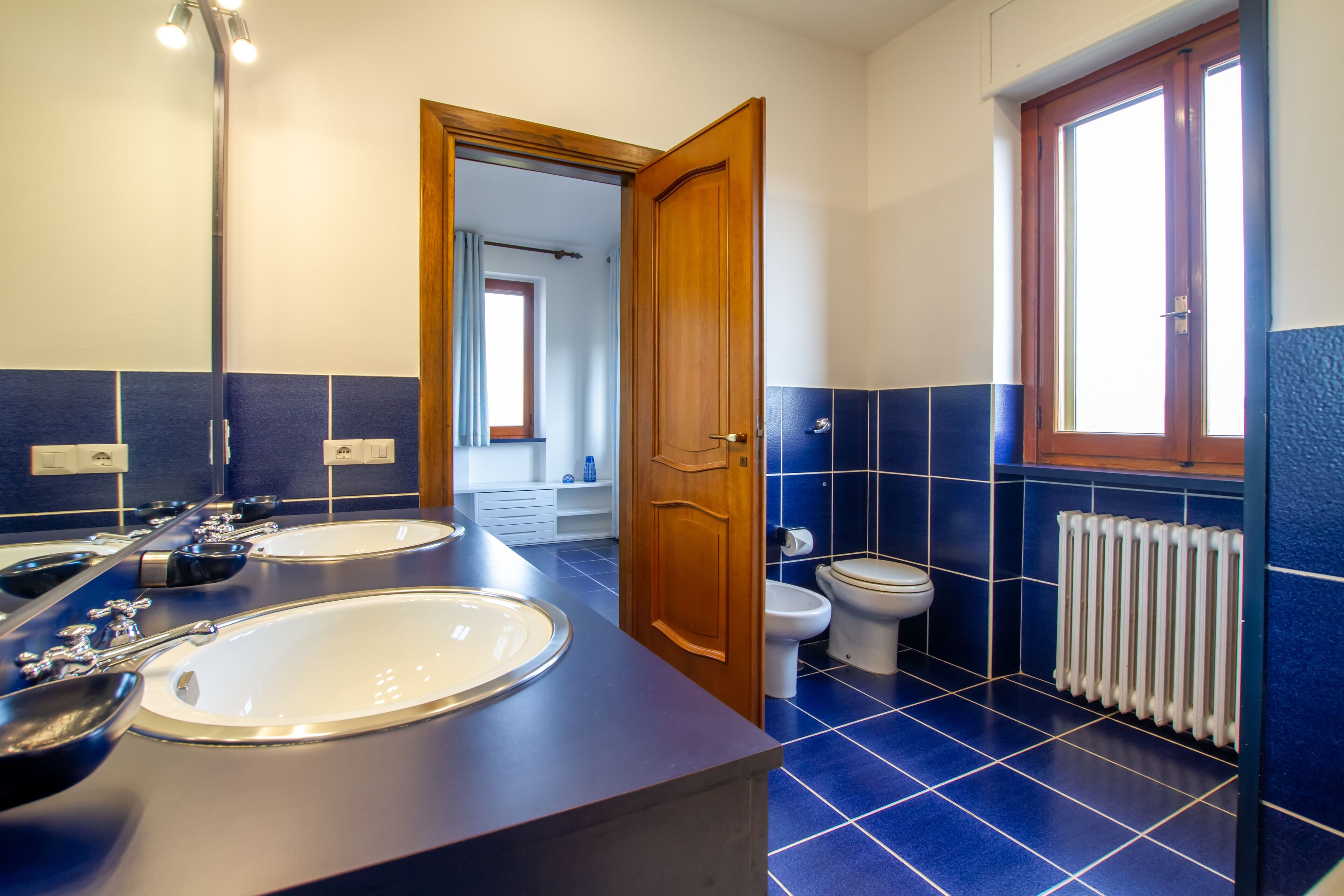 Un baño con dos lavamanos, un inodoro y una ventana.