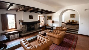 A living room with a fireplace, leather sofas, a patterned rug, and an arched doorway. - Villa in Piedmont with private pool in beautiful vineyard of Tenuta CostaRossa (Piemonte)