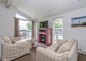 Une pièce chaleureuse avec deux canapés à rayures, une cheminée et une vue sur l’extérieur.