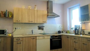 Eine Küche mit Holzausstattung, einer Mikrowelle, einem Toaster und einem Fenster mit Tageslicht.