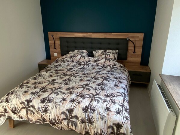 A bedroom with a bed, wooden headboard, and a nightstand.