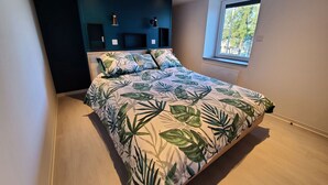 Ein modernes Schlafzimmer mit einem Bett, einem Fenster und einer dunkel gestalteten Wand.