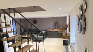 Ein modernes Interieur mit Treppe, einer Couch, einer Essecke und einer Küche.