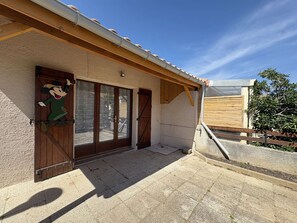 A building with a wooden door, a window, and a small porch area.