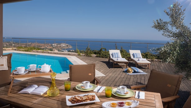 A wooden deck with a pool, lounge chairs, and breakfast setup overlooking the sea. - Luxury Villa Hara with private pool (Malevizi)