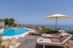 En säsongsöppen utomhuspool, parasoller och solstolar