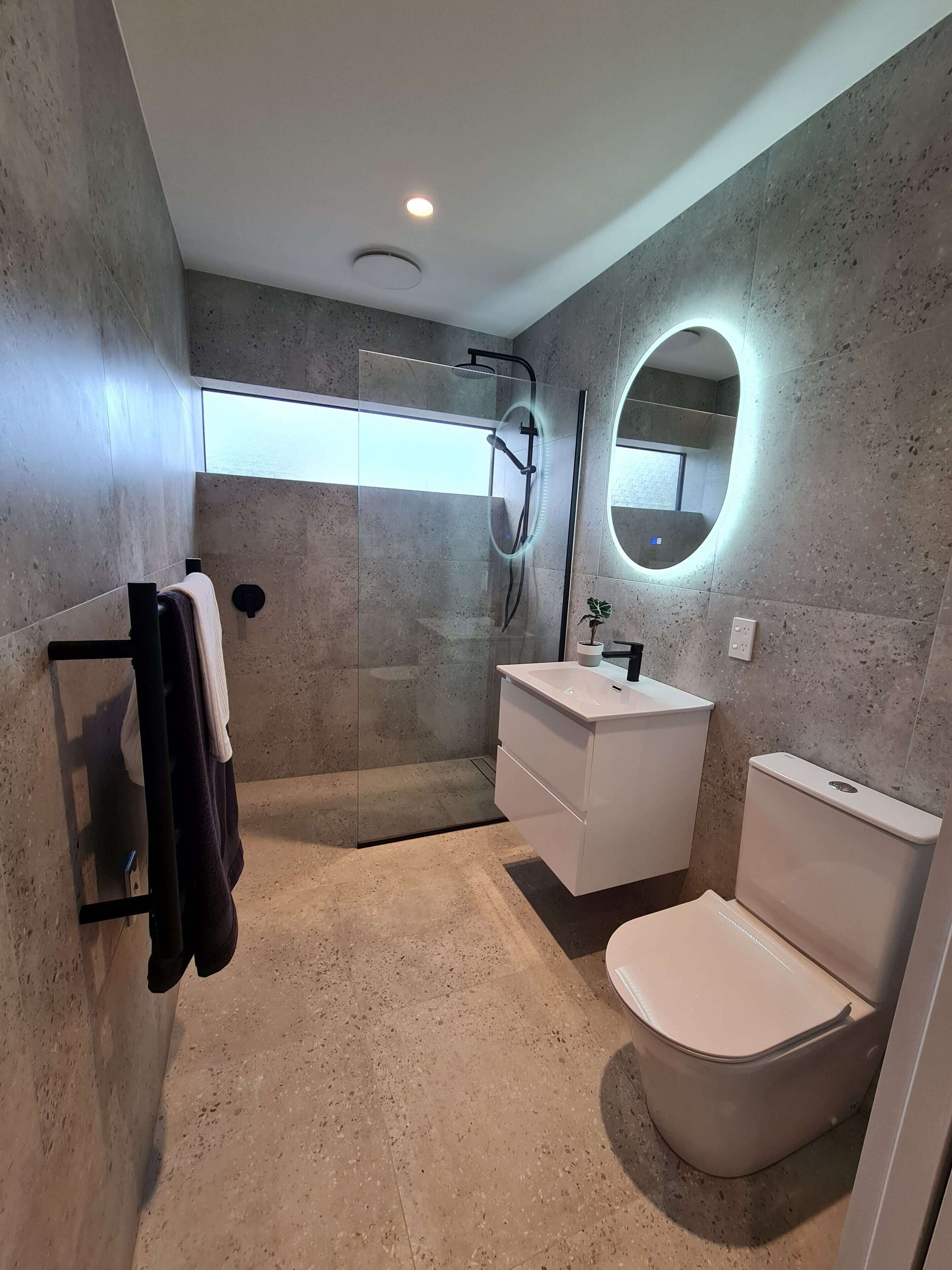 A modern bathroom with a glass-enclosed shower, a white sink, and a toilet.