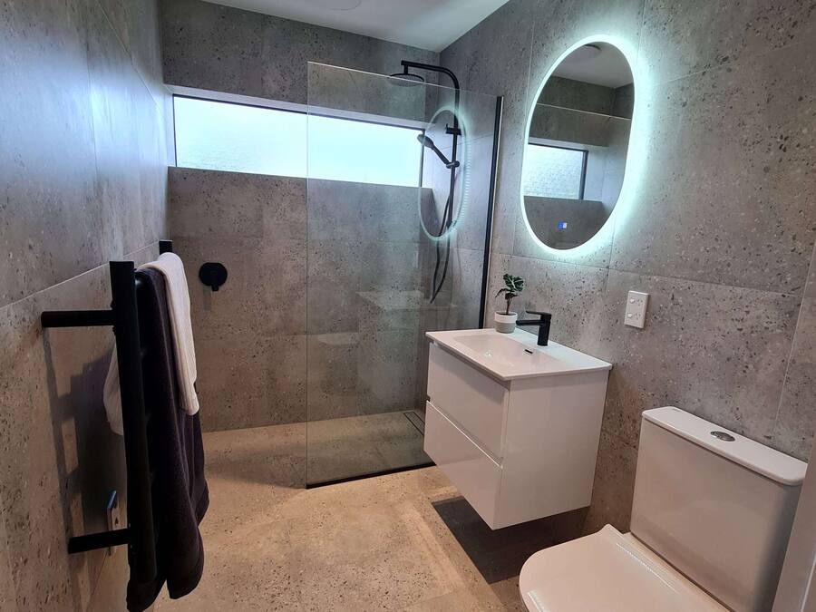 A modern bathroom with a glass-enclosed shower, a white sink, and a toilet.