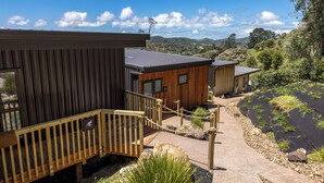 A modern building with a wooden deck and a staircase leading to a door marked "FLYIN' SOUTH." - Hidden Valley Waiheke (Waiheke Island)
