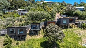 A hillside residential area with modern houses, some with decks and large windows, surrounded by lush greenery. - Hidden Valley Waiheke (Waiheke Island)