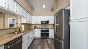 A modern kitchen with white cabinets, stainless steel appliances, and a granite countertop.