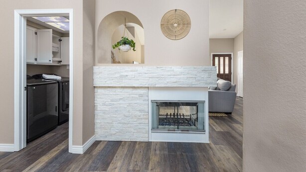 A modern living room with a fireplace, a stone accent wall, and a hanging plant.