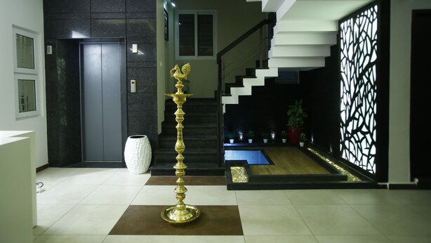 Un lobby moderno con una escalera, un objeto dorado decorativo y un jarrón blanco.