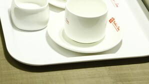 Una bandeja con cuatro tazas blancas y dos pequeños recipientes de vidrio.