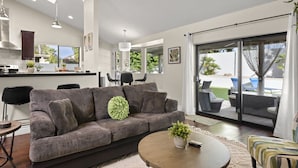 A modern living room with a grey sofa, a round coffee table, and a view of the outdoor patio through a sliding glass door. - Perfectly Located Spacious Home with Heated Pool (Scottsdale)
