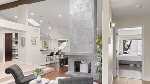 A spacious living area with a stone fireplace, modern furniture, and a view of a balcony. - Perfectly Located Spacious Home with Heated Pool (Scottsdale)