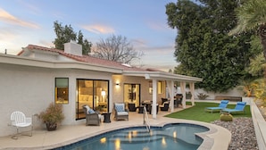 A modern house with a swimming pool, outdoor seating, and a well-maintained lawn. - Perfectly Located Spacious Home with Heated Pool (Scottsdale)