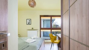 Un dormitorio moderno con cama, escritorio y silla. Se ve un ventanal con vistas al exterior.