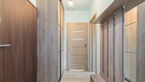 Un pasillo con taquillas de madera, un banco y una lámpara.