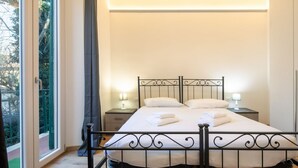 Un dormitorio con cama, dos mesitas de noche, una ventana con cortinas y vistas al exterior.