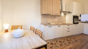 Una cocina compacta con armarios de madera, un lavamanos y una mesa de comedor con sillas.