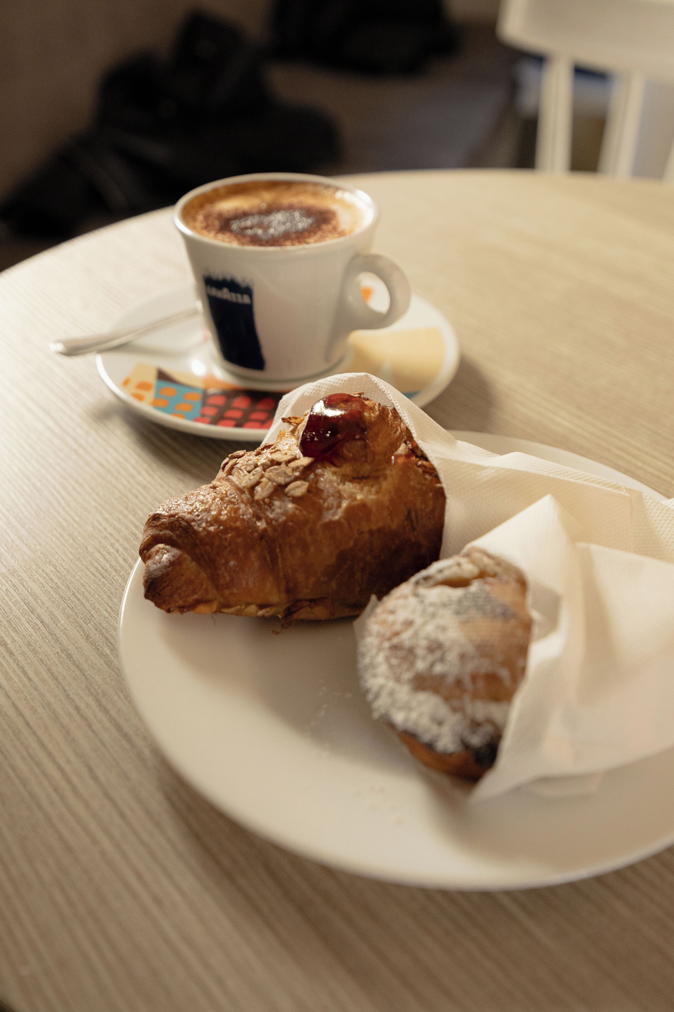 A plate with a pastry and a cup of coffee on a table.
